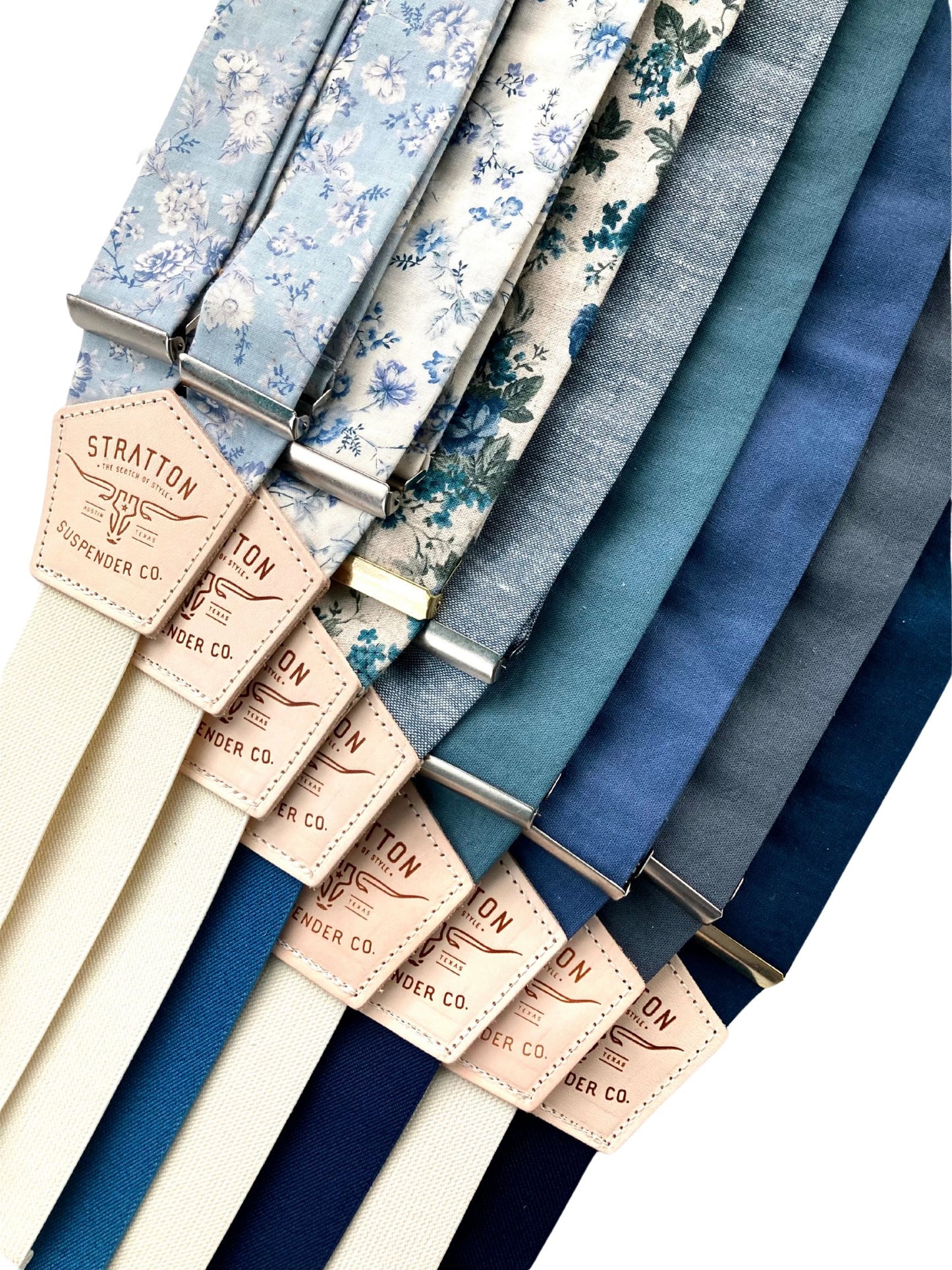 A collection of handmade linen button-on suspenders in powder blue floral, Victorian cornflower blue floral, rustic blue floral, sky blue with ocean blue, teal, French blue with navy, slate blue, and navy with midnight blue. Perfect for weddings, groomsmen, and vintage menswear.