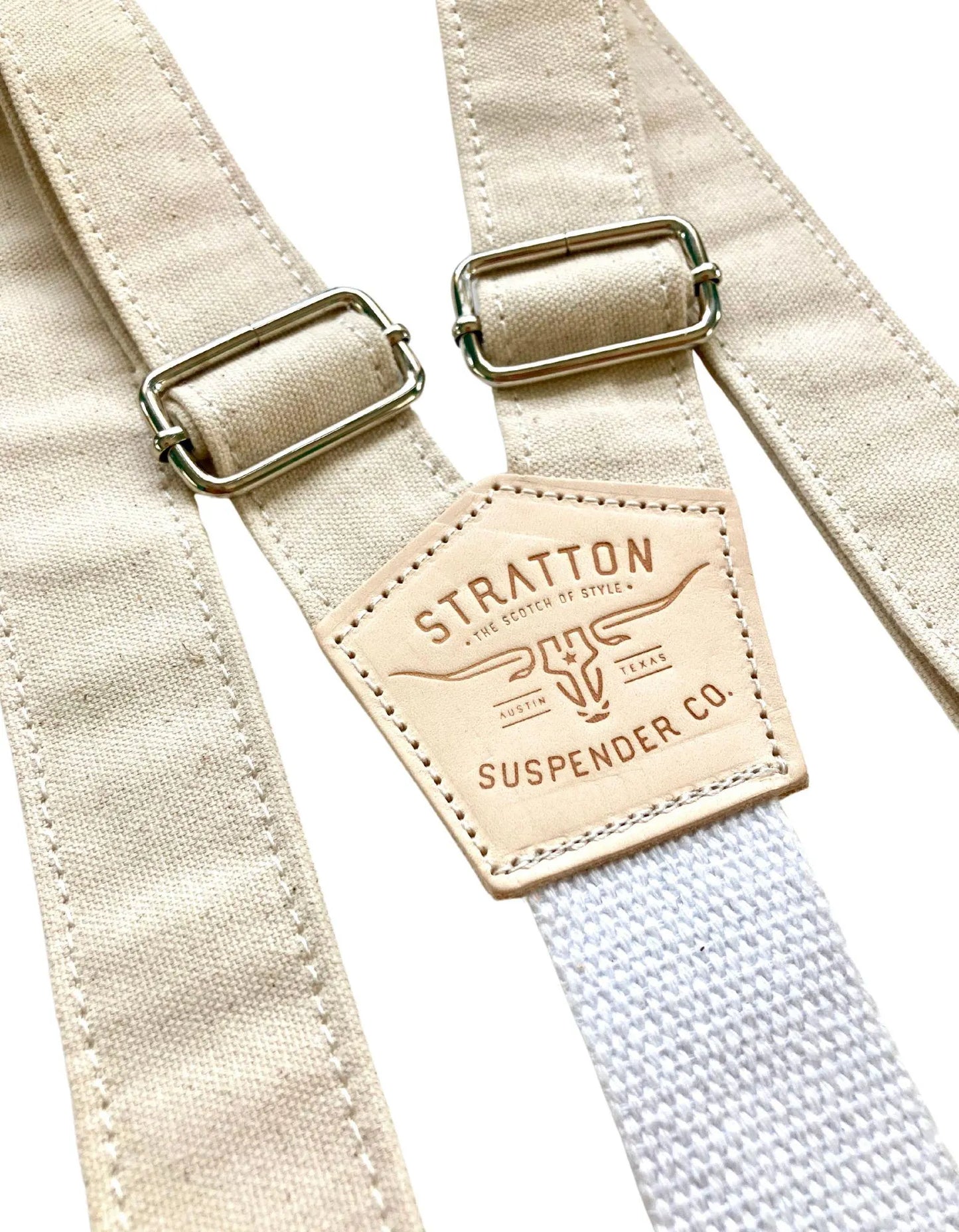 Close-up of beige rustic canvas wedding suspenders featuring antique brass adjusters, heavyweight cotton webbing back strap, and full-grain leather patch; handcrafted in the USA for groomsmen and western wedding attire.