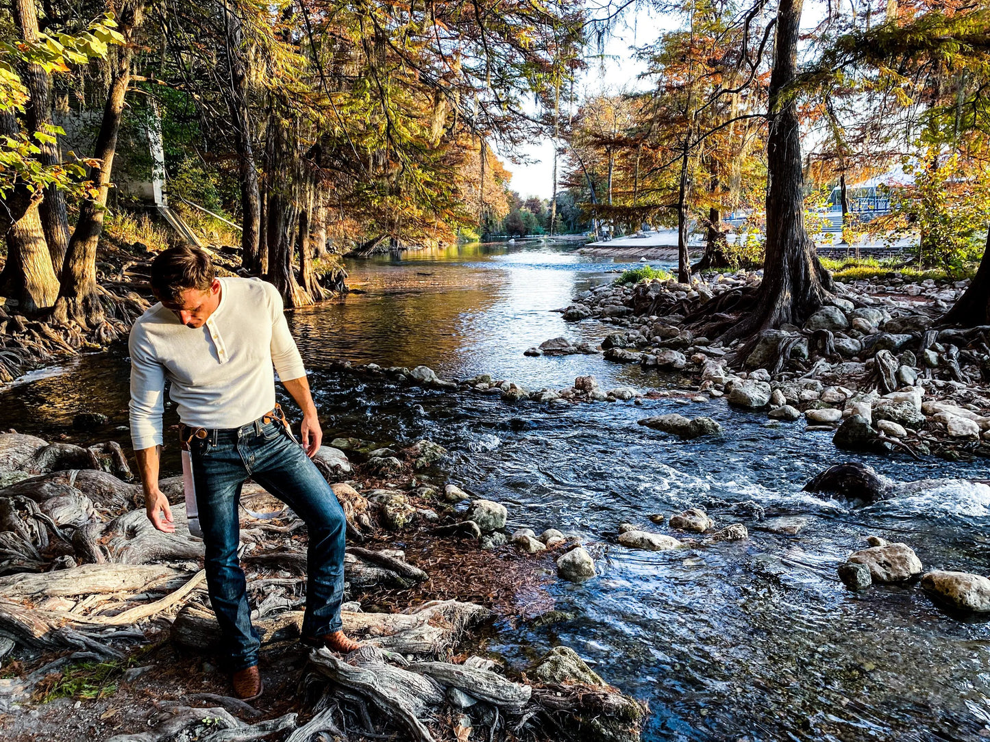 Vintage beige suspenders with magnetic clasps styled with Henley and Levi’s near a scenic Texas Hill Country river.