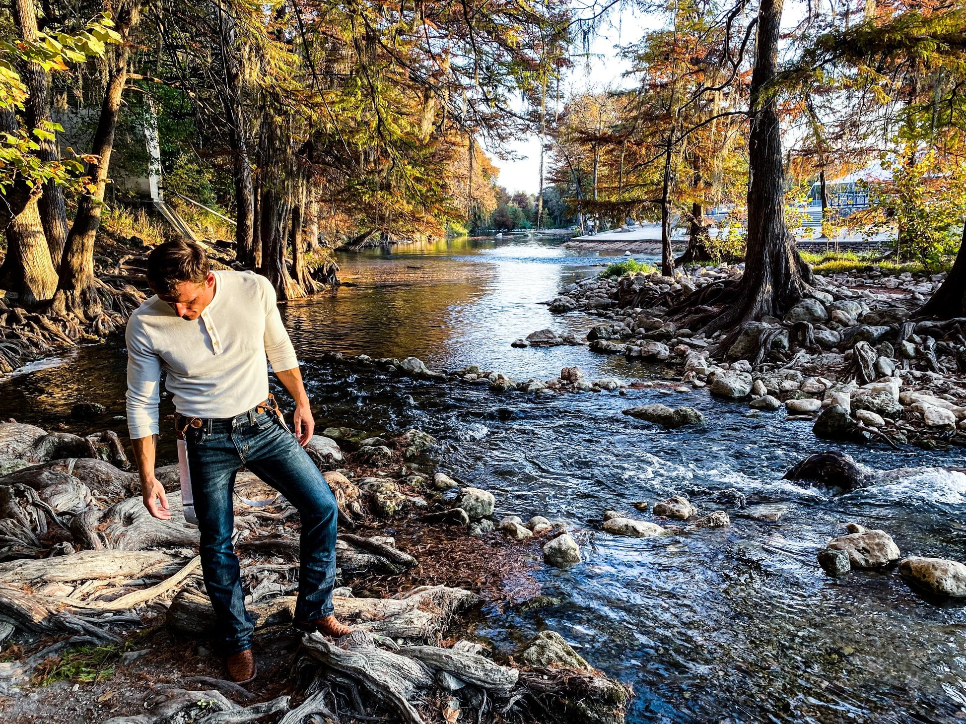 Vintage beige suspenders with magnetic clasps styled with Henley and Levi’s near a scenic Texas Hill Country river.