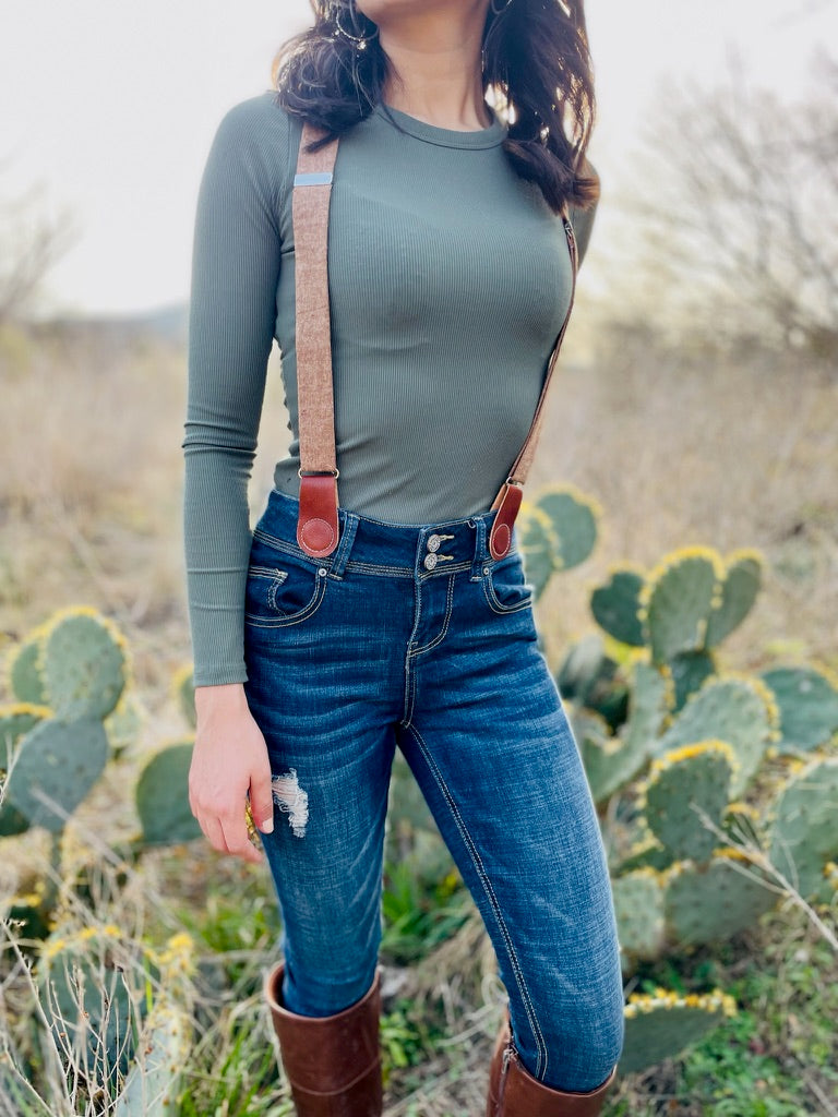 Brown women’s suspenders with magnetic leather clasps, handmade in Texas, styled for fall fashion with jeans and boots.