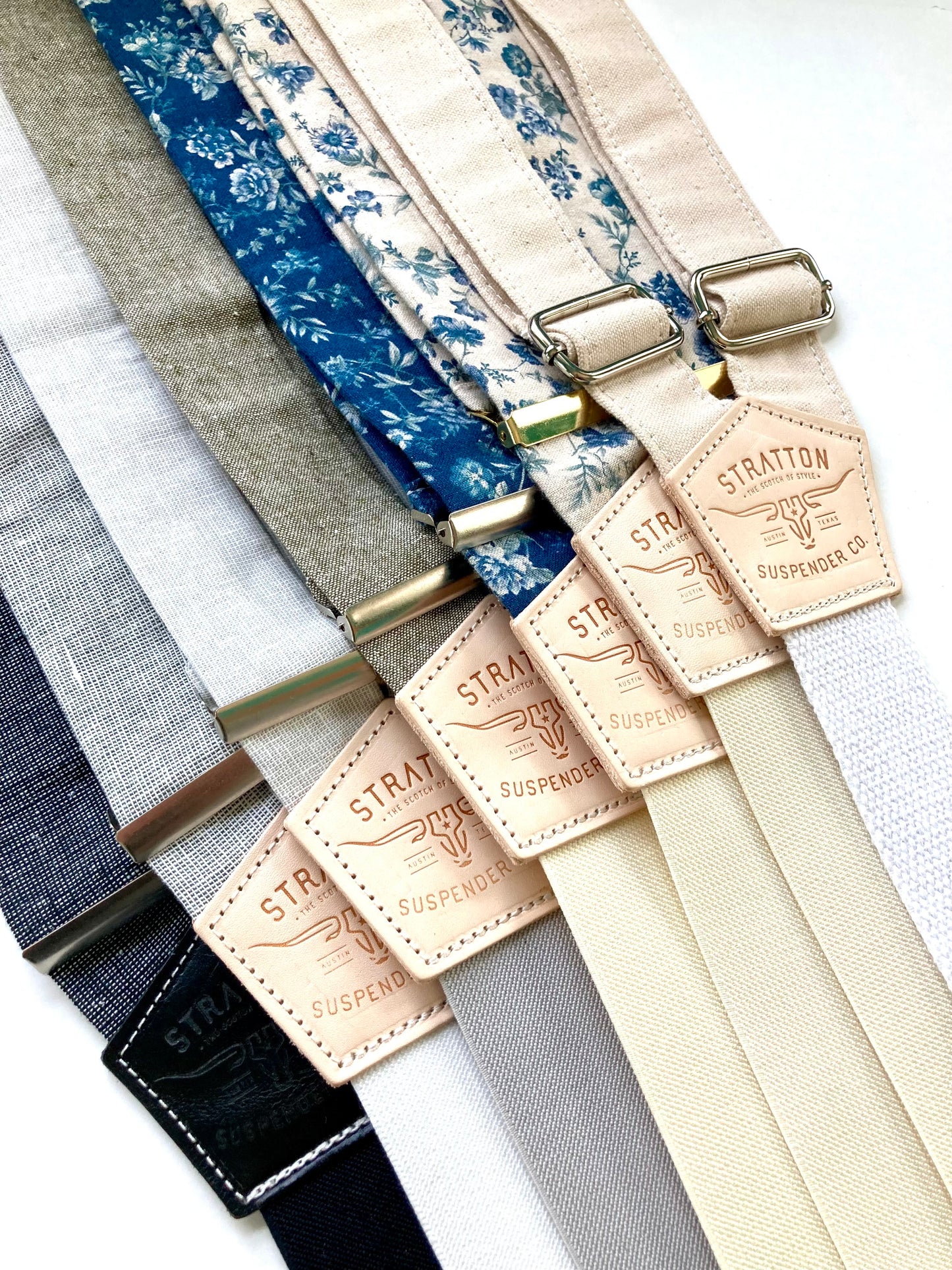Assorted handmade canvas and floral suspenders with vintage-inspired designs, featuring heavy-duty cotton webbing and button-on style with polished hardware—ideal for rustic weddings, vintage formalwear, or Western menswear.