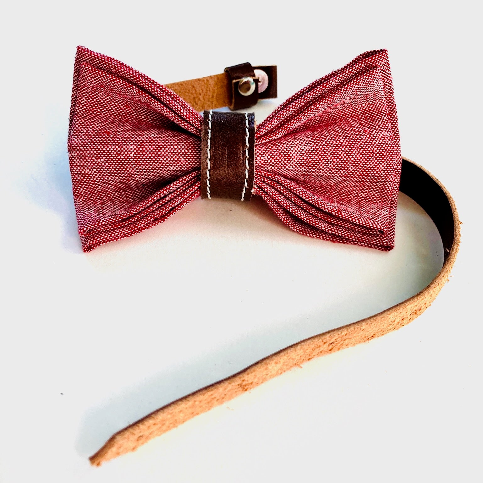 Handmade children’s red linen bow tie with rich chocolate leather accents—adjustable, pre-tied, and perfect for formal events or holidays.