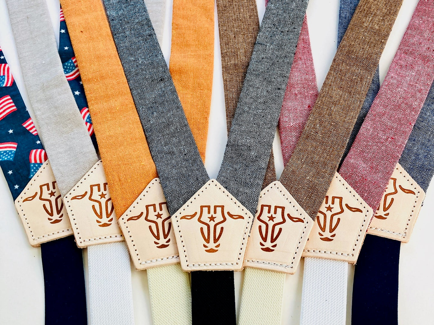 Children’s magnetic clasp suspenders in assorted linen colors with embossed leather back patches, shown in a colorful side-by-side collection.