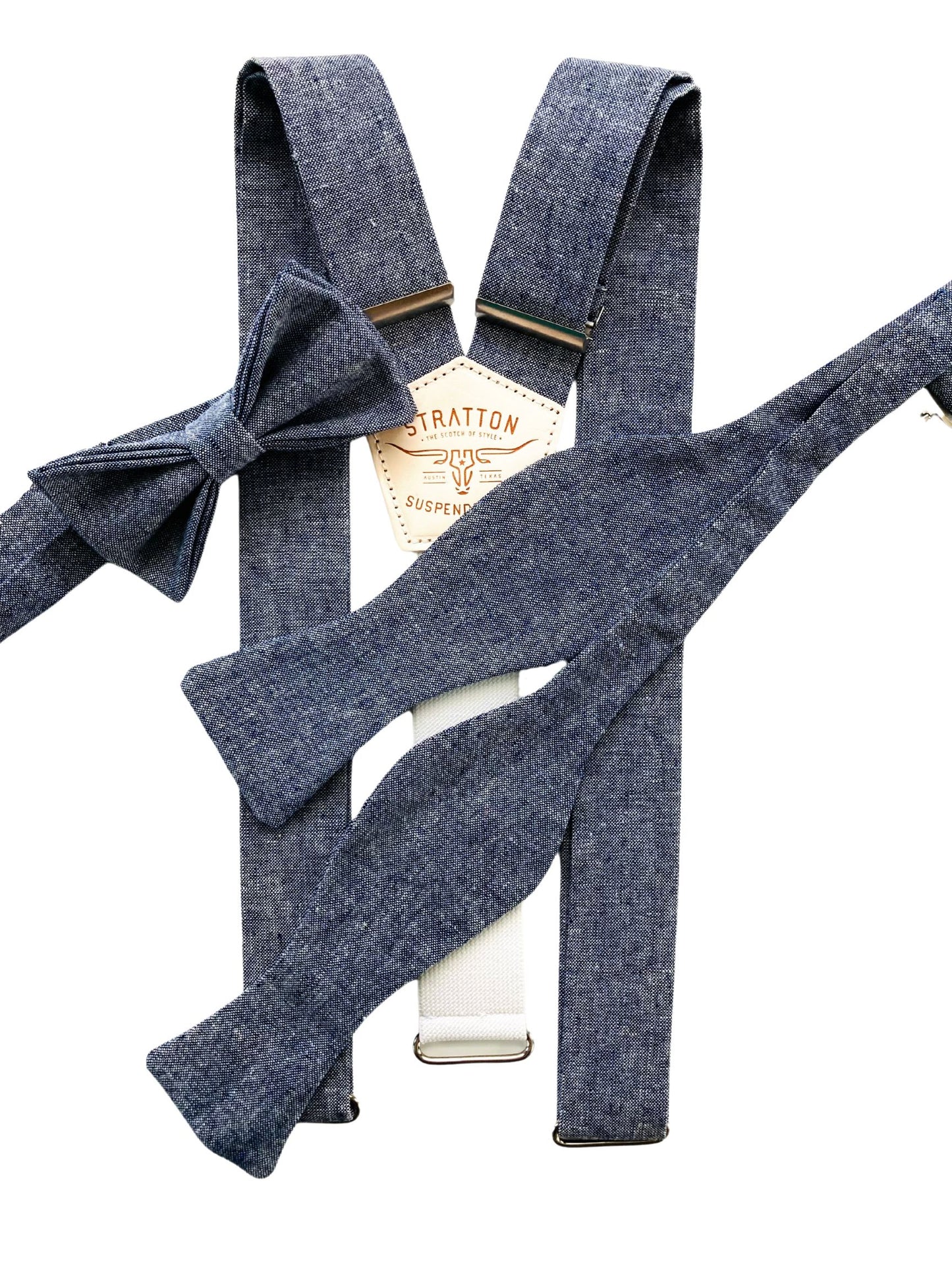 Denim blue linen suspenders paired with matching pre-tied and self-tie bow ties, featuring Stratton Suspender Co. embossed leather patch. A refined handmade set for groomsmen or vintage-inspired formalwear.