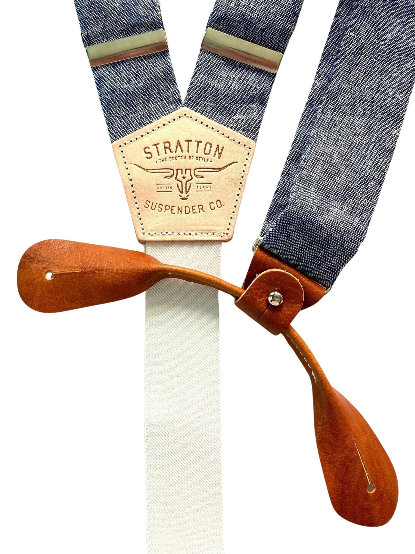 Close-up of denim blue linen suspenders with full-grain brown leather button-on tabs and Stratton Suspender Co. branded patch, ideal for formalwear and weddings.