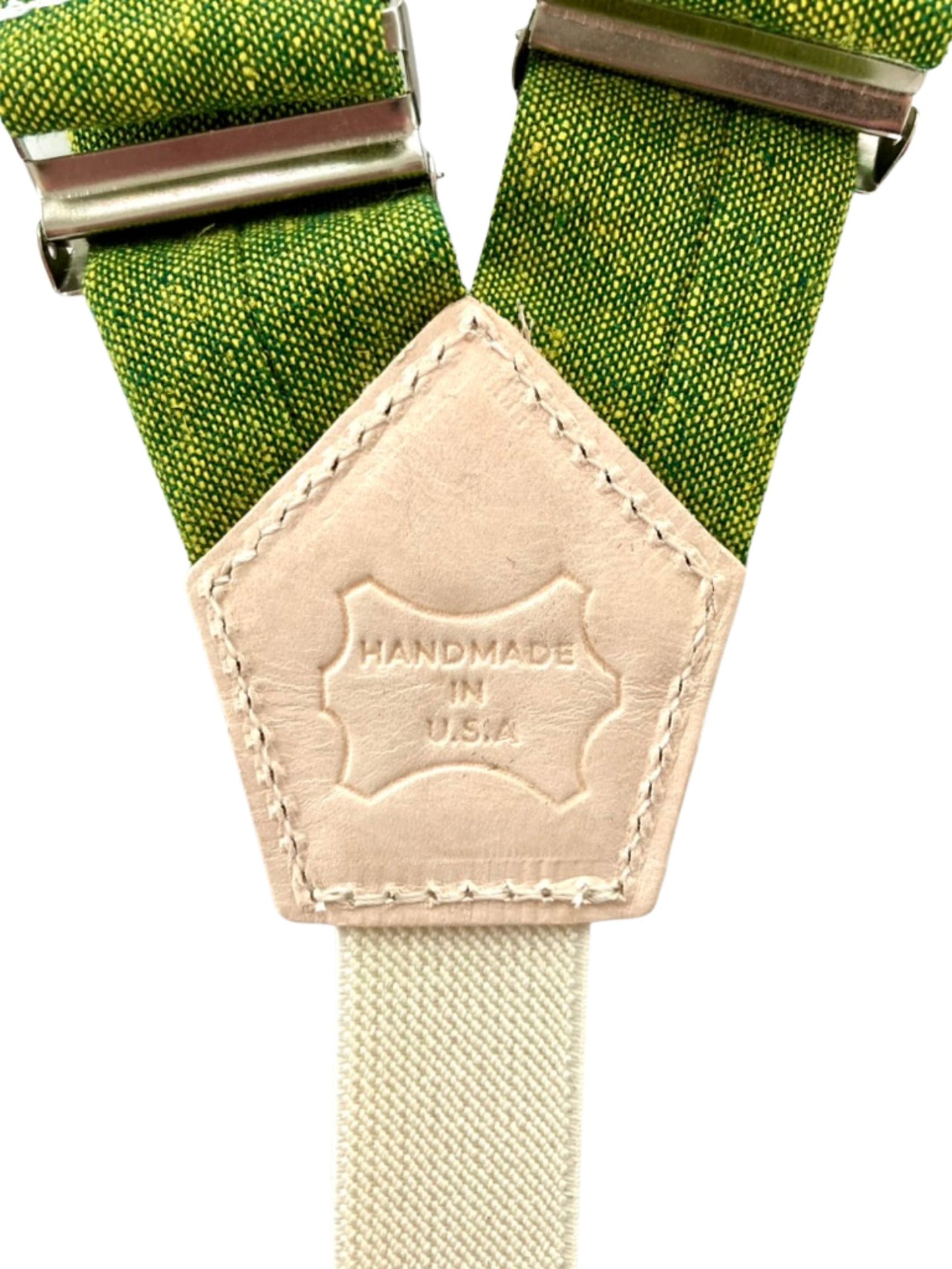 Close-up of natural leather patch embossed with “Handmade in USA” on chartreuse green linen women’s suspenders.
