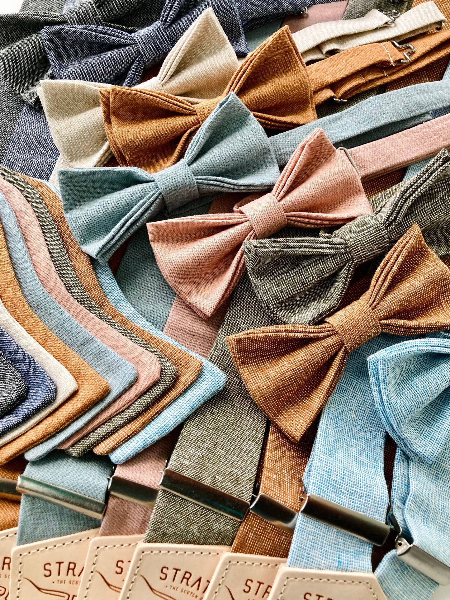 Linen self-tie and pre-tied bow ties displayed with coordinating handmade suspenders, designed for groomsmen, wedding parties, and formal occasions. Elegant color palette and refined craftsmanship.