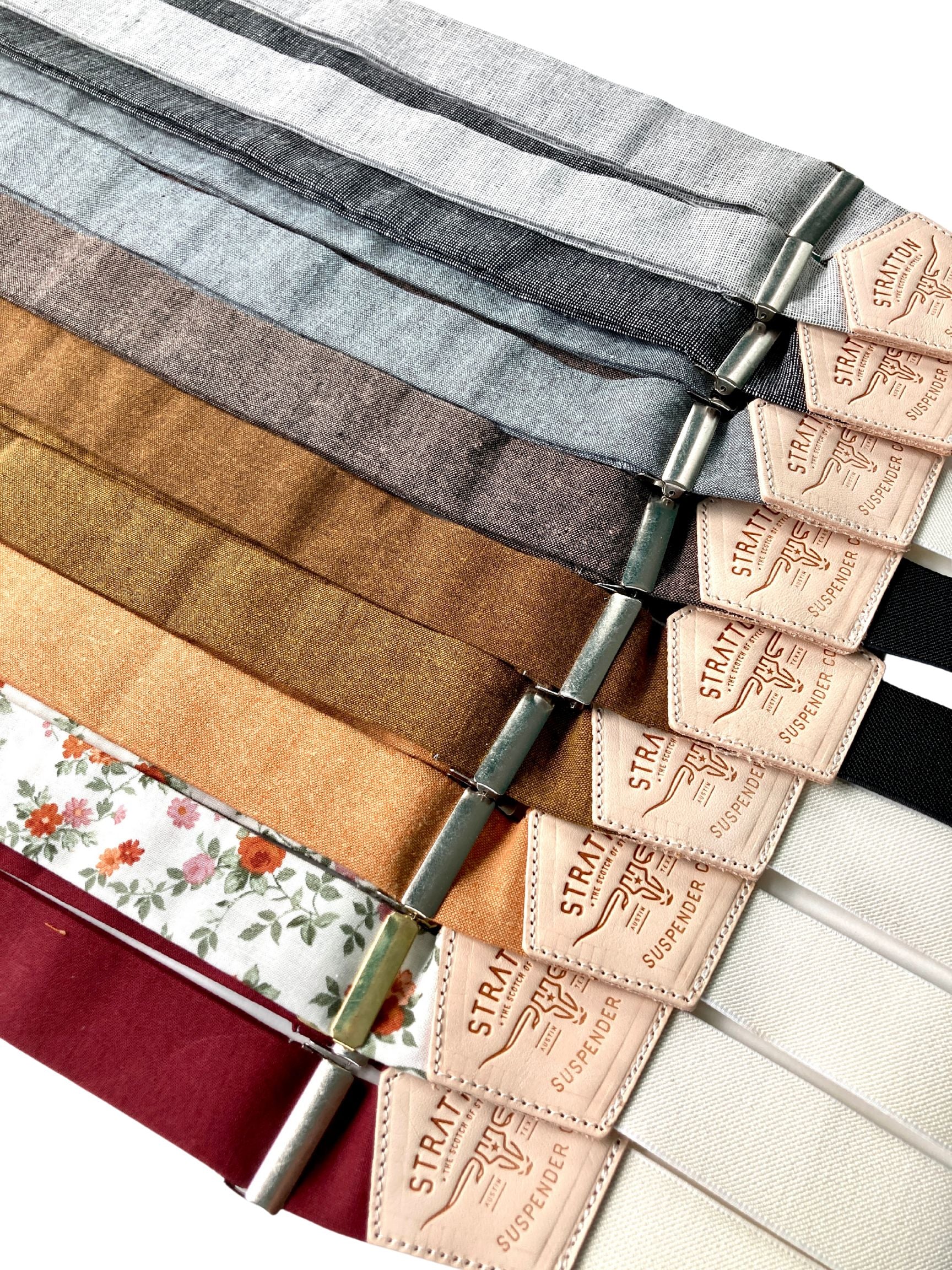 A collection of handmade linen button-on suspenders in rustic shades like espresso, shale, cinnamon, copper, and terracotta floral — classic menswear accessories designed for weddings, heritage fashion, and vintage-inspired style, crafted in Texas.