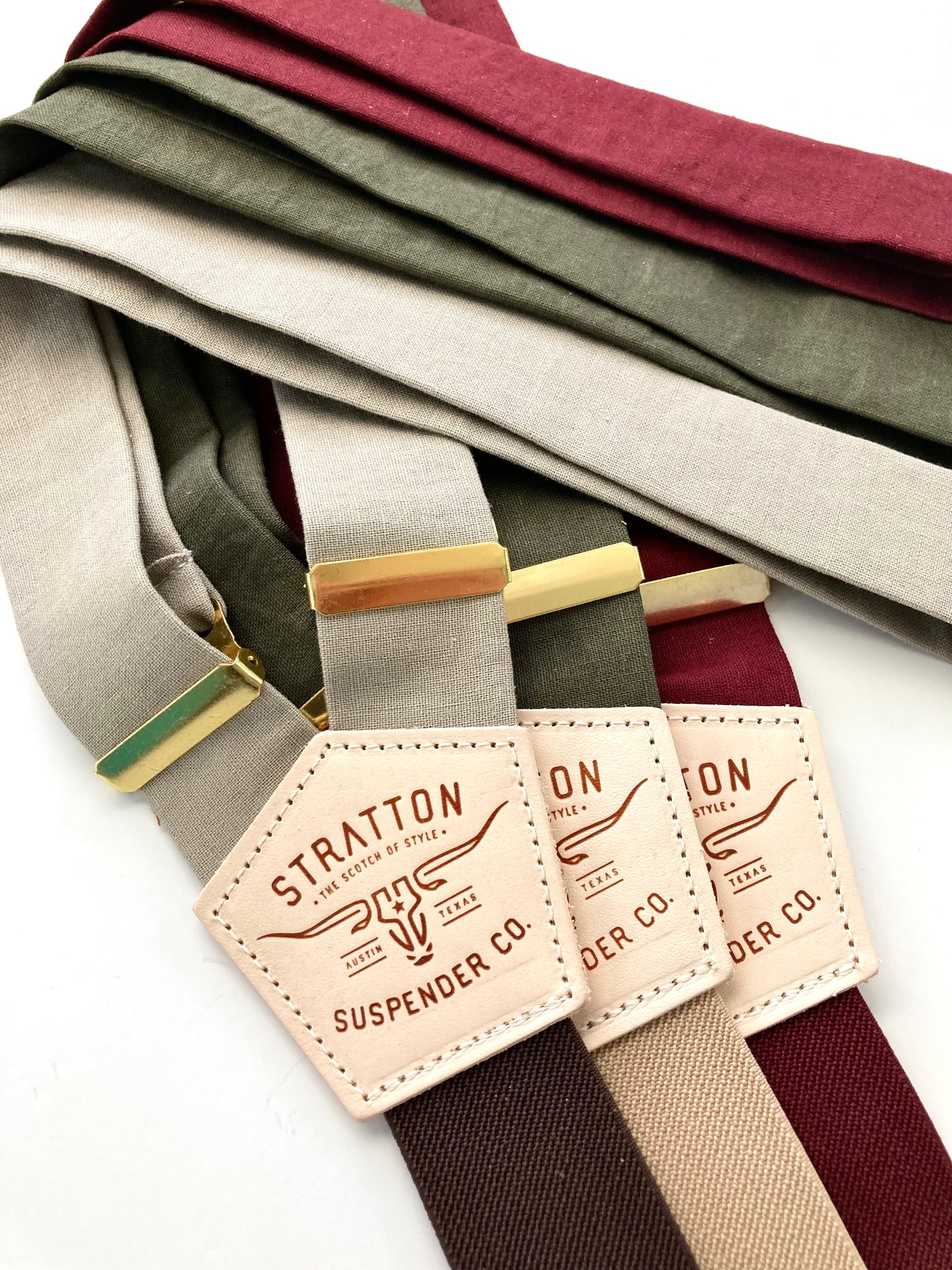 Neutral-toned linen suspenders for weddings, shown in burgundy, olive, and taupe with gold adjusters and leather detailing.