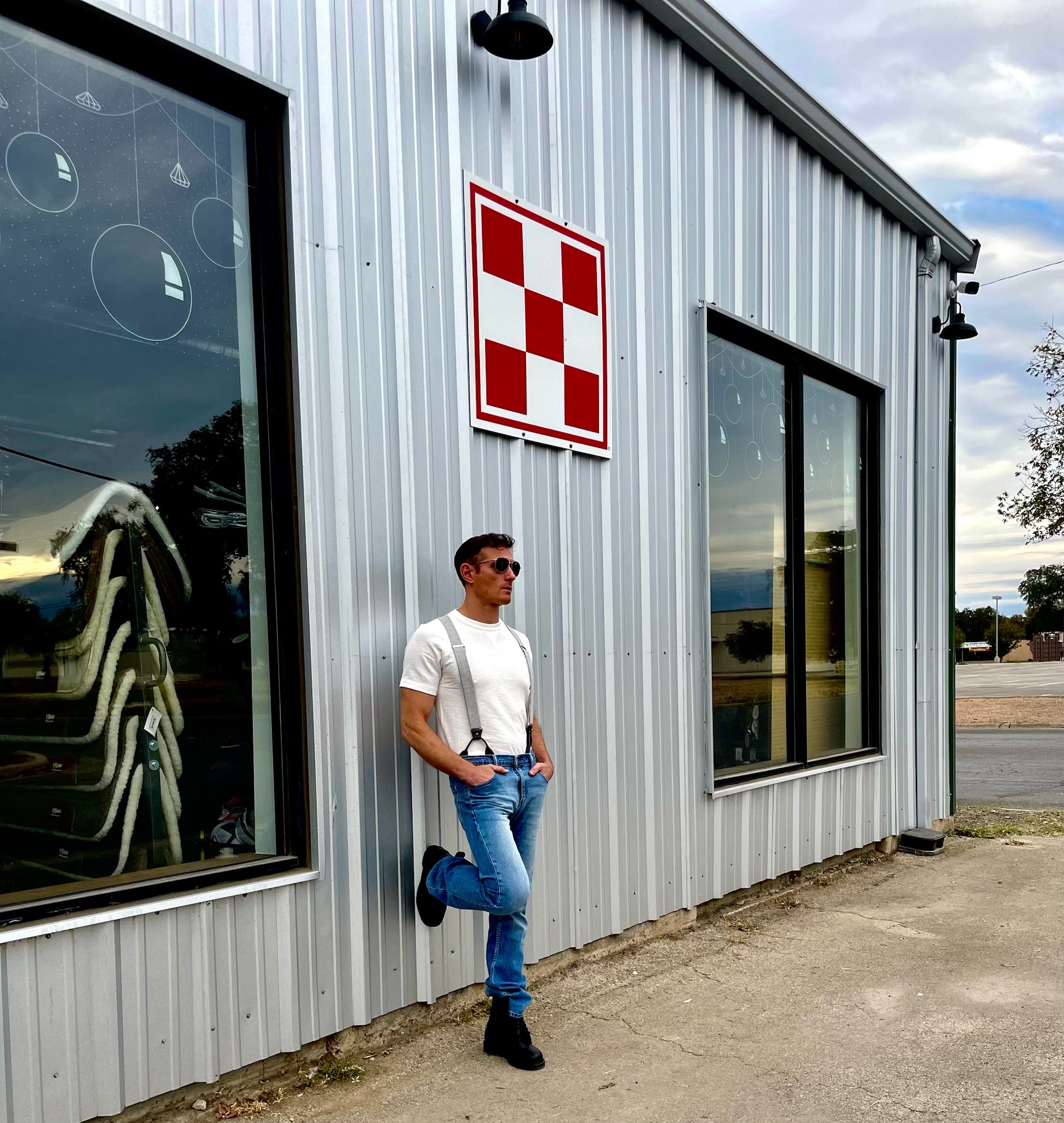 Man wearing Stratton Suspender Co. charcoal gray linen suspenders with jeans and boots outside Texas Farm Store, showcasing casual wedding and formalwear style.