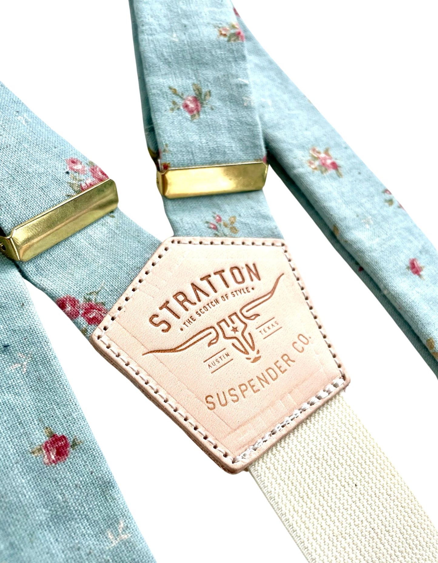Close-up of powder blue vintage floral linen suspenders with gold hardware and Stratton Suspender Co. leather back patch, handmade in Texas for weddings and formal menswear.