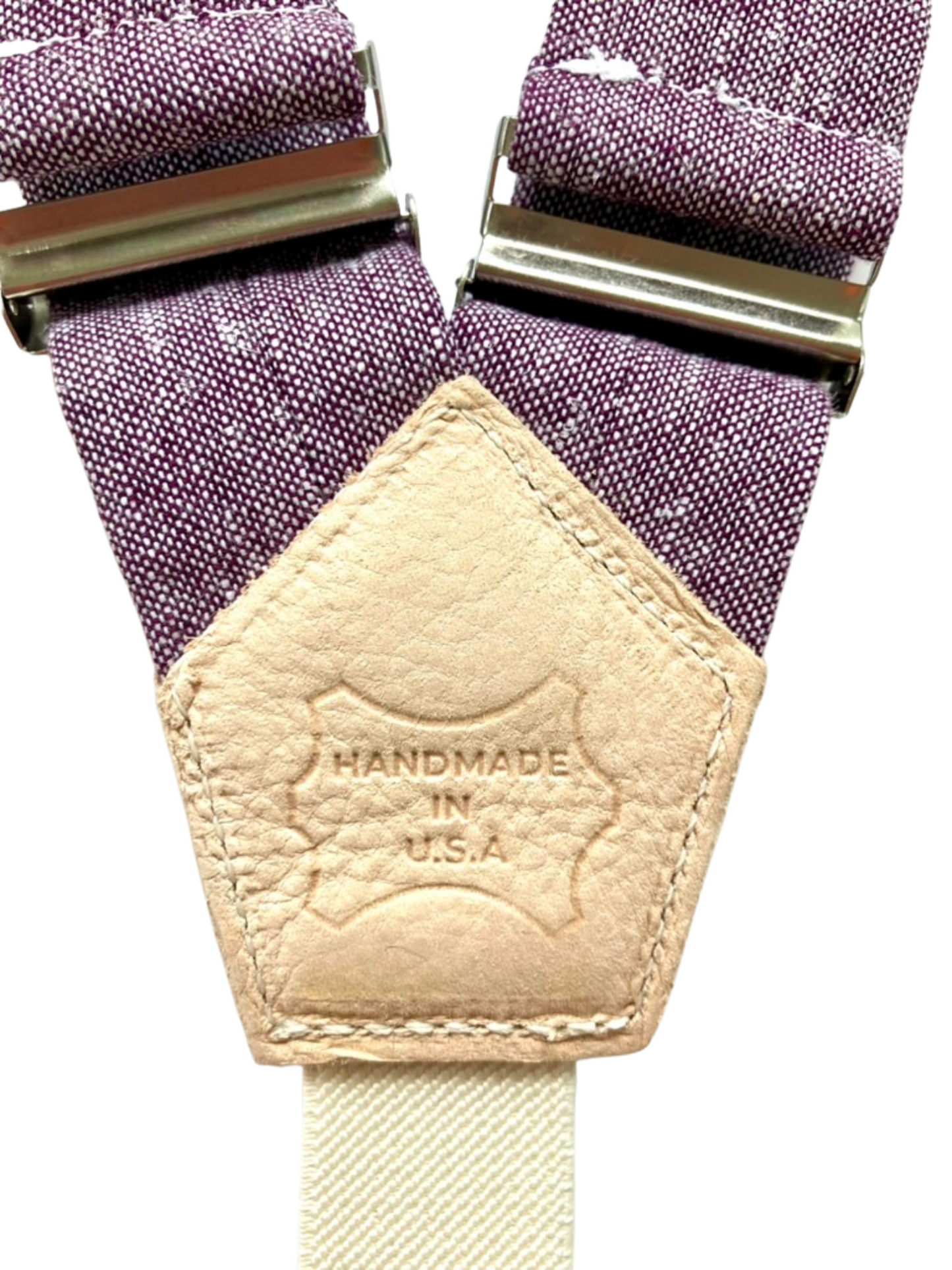 Close-up of genuine leather back patch on purple women’s suspenders with 'Handmade in U.S.A.' stamp, showcasing artisan craftsmanship.