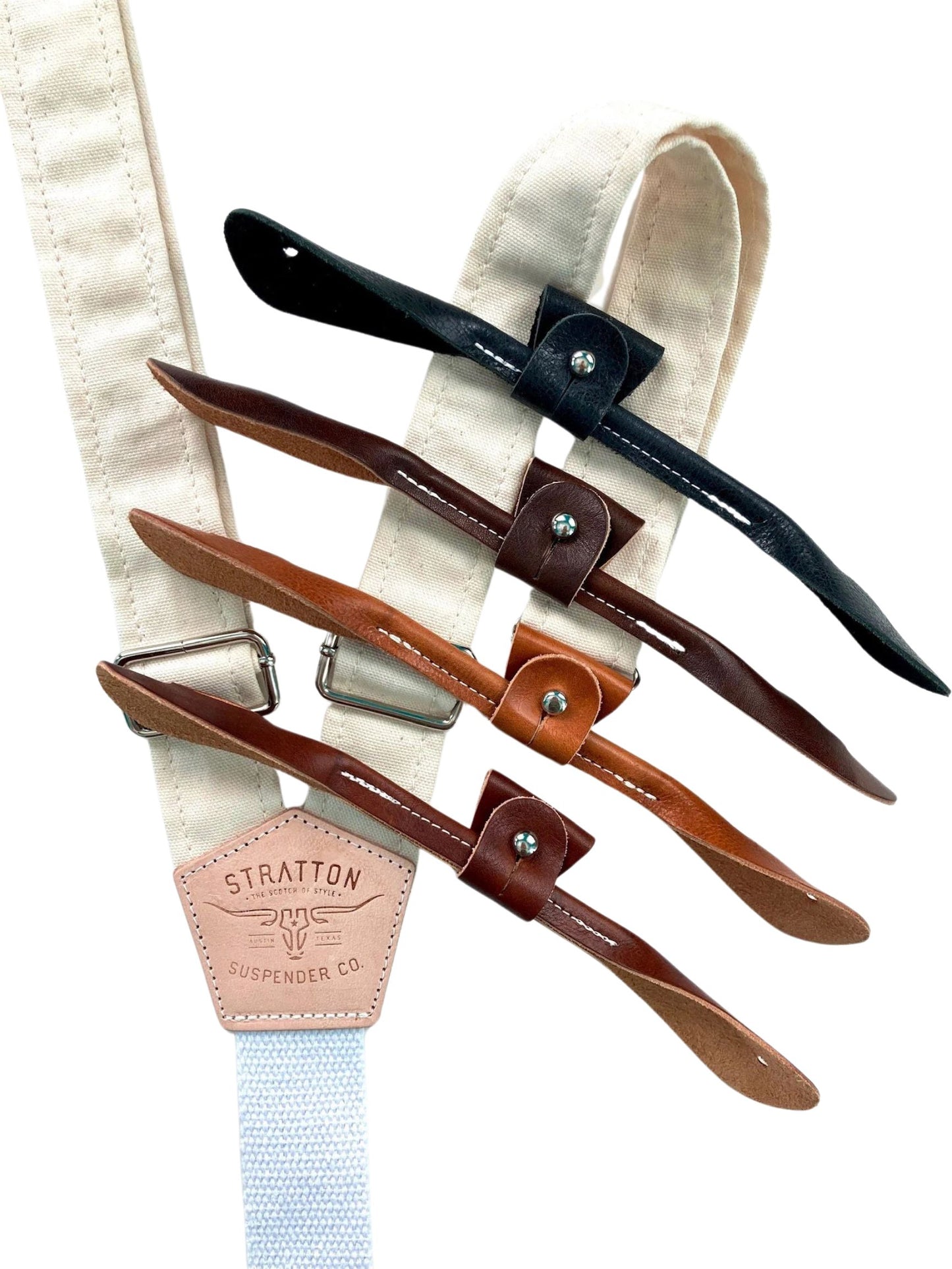 Rustic beige canvas button-on suspenders with full-grain leather strap options in black, dark brown, chestnut, and cognac; durable Y-back braces with heavyweight cotton back strap and antique brass adjusters, ideal for heritage menswear, workwear, or rustic weddings.