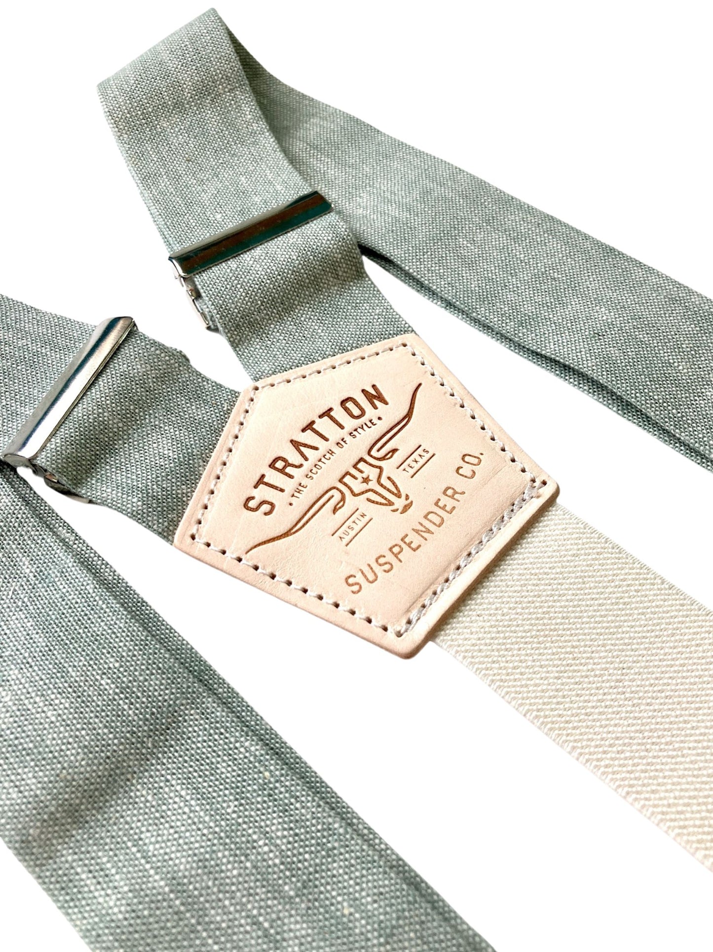 Close-up of sage green Brussels linen suspenders with cream elastic back strap and metal adjusters, featuring Stratton Suspender Co. branding—handmade in Texas for rustic weddings and groom or groomsmen attire.