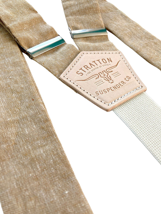 Close-up of tan linen suspenders with cream elastic back strap and Stratton Suspender Co patch, showcasing textured natural fabric and metal adjusters, handmade in Texas for weddings and classic menswear.