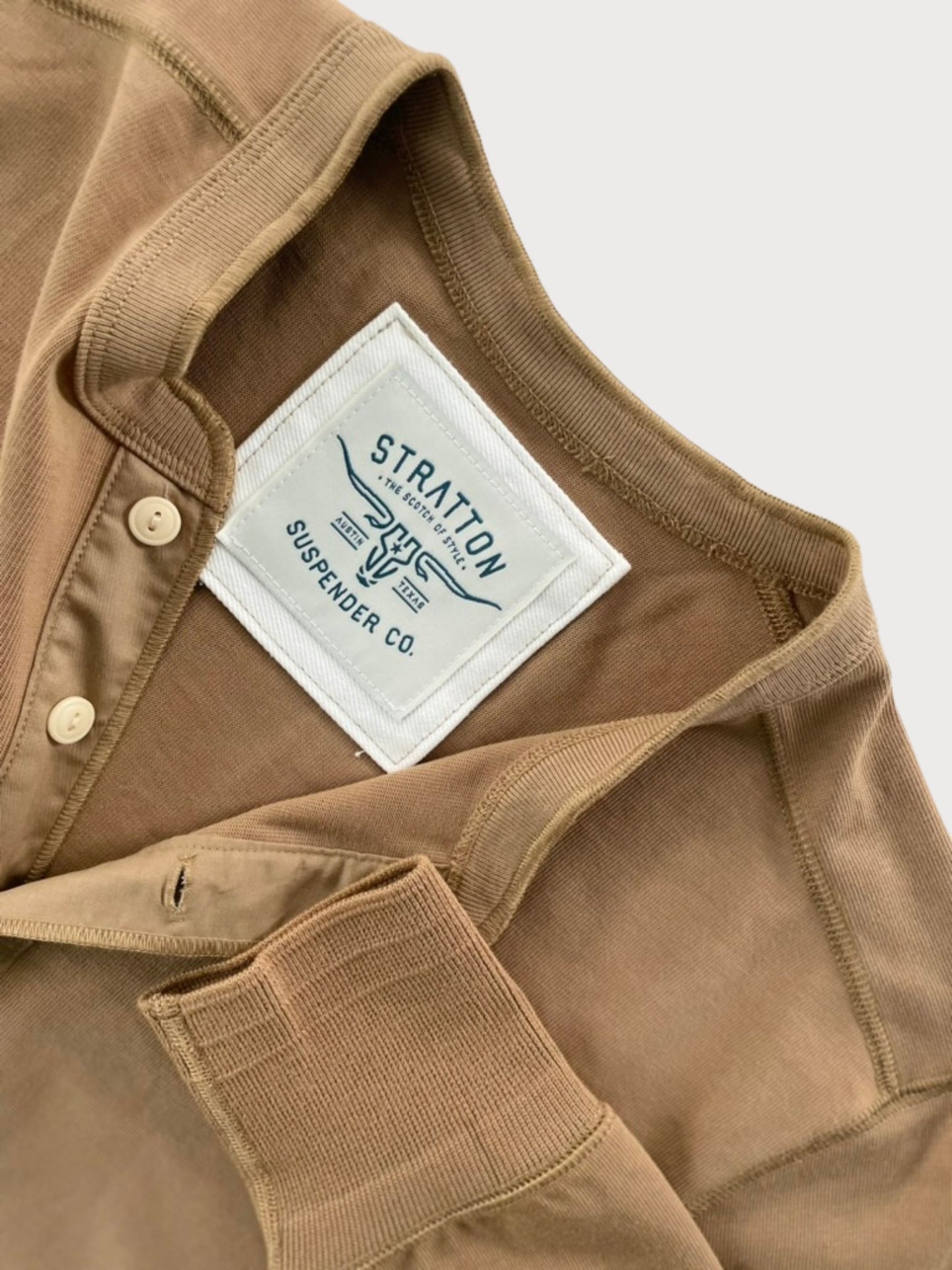 Close-up of Vintage 1940s Tobacco Brown Heavyweight Henley by Stratton Suspender Co., showcasing the ribbed sleeve cuff, three-button placket, and embroidered brand label. Made in the USA from heavyweight cotton for durability and classic heritage workwear style.