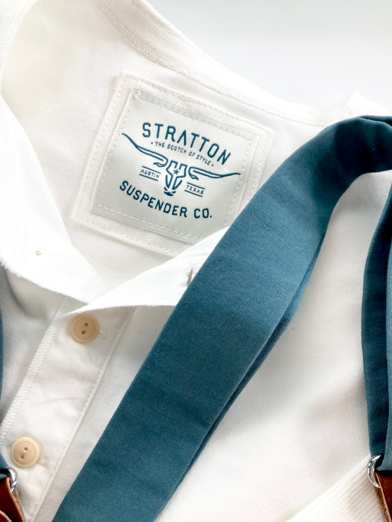 Vintage 1940s White Heavyweight Henley by Stratton Suspender Co., paired with Slate Blue Heritage Linen Suspenders. Features three-button placket, ribbed cuffs, and embroidered label. Made in the USA for durability and classic workwear style.