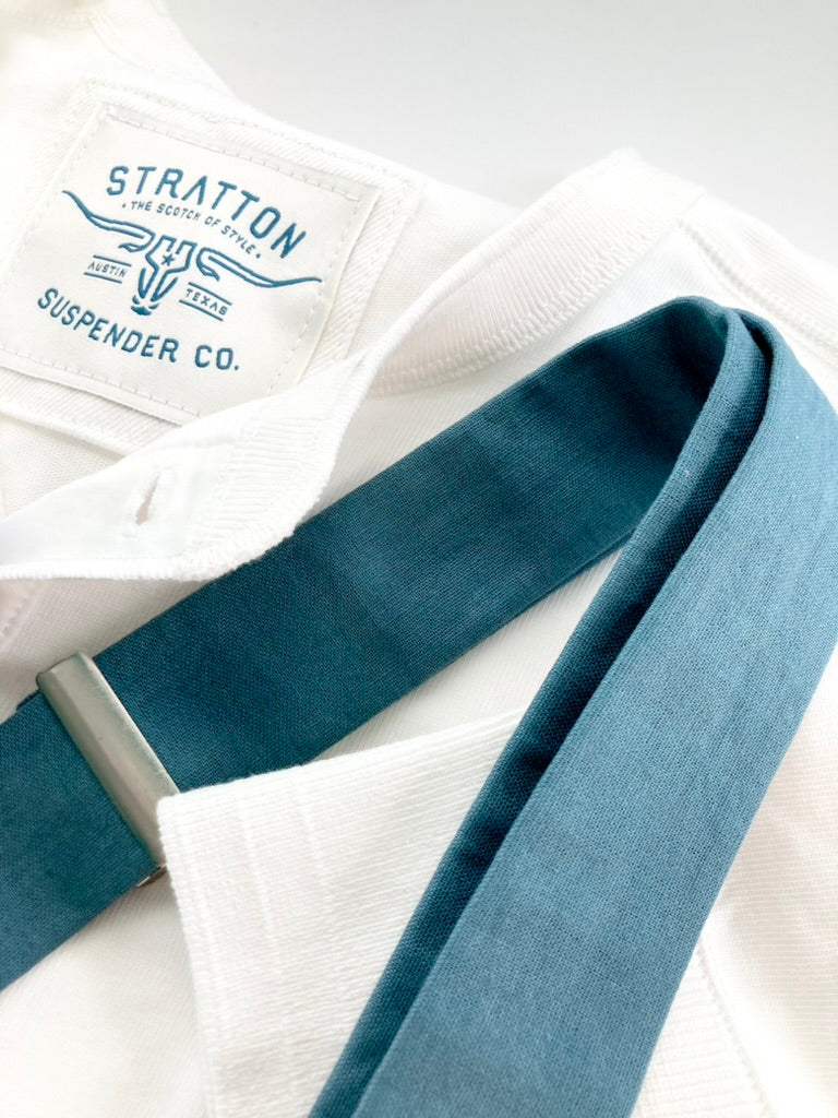 Vintage White Henley by Stratton Suspender Co. styled with blue slate linen suspenders featuring a silver adjuster. Showcases ribbed cuffs and embroidered brand label, highlighting American heritage craftsmanship and timeless workwear-inspired design.