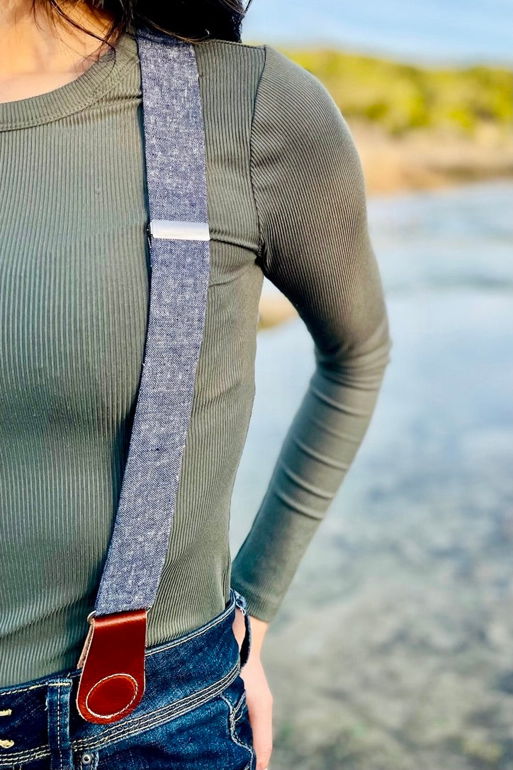 Lifestyle photo of women’s linen suspenders with leather magnetic clasps, styled with dark denim and a fitted long-sleeve top.