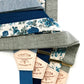 A collection of blue linen and floral wedding suspenders with deep blue, cream, and gray elastic back straps. Features handcrafted leather back patches and gold-tone adjusters. Premium suspenders for rustic weddings, groomsmen, and heritage menswear. Ethically made for a classic, timeless style.