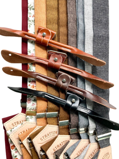 A collection of handcrafted linen suspenders in earthy tones, featuring brown and black leather button ends. Ethically made by Stratton Suspender Co., these vintage-style suspenders are perfect for groomsmen, rustic weddings, and timeless menswear.