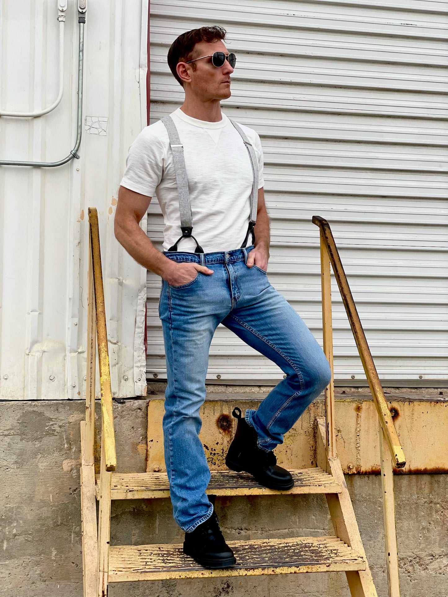 Man wearing handmade Charcoal Linen Suspenders with black leather button-on attachments, fitted vintage white tee, and classic denim jeans. Styled with black boots for a rugged yet refined heritage menswear look. Ethically handmade in Texas by Stratton Suspender Co.