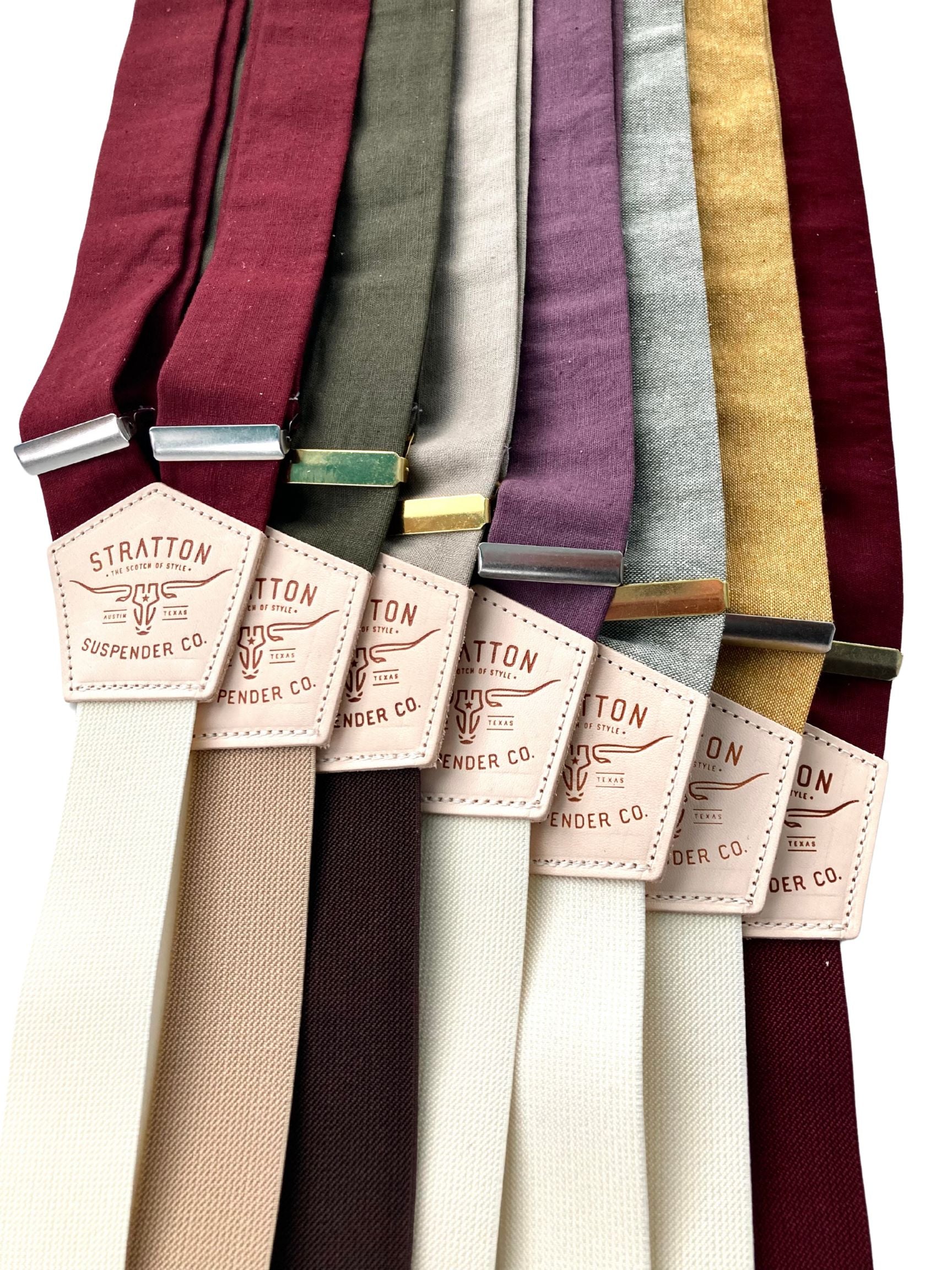 Groomsmen suspenders in rustic linen fabrics with silver and gold hardware, shown in earthy wedding colors like burgundy, plum, moss, and marigold.