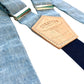 Close-up of light blue linen suspenders with a navy twill elastic back strap and vegetable-tanned leather back patch. Ethically handmade by Stratton Suspender Co. These premium button-on suspenders are perfect for weddings, groomsmen, and vintage menswear enthusiasts.