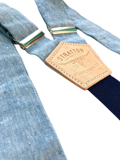 Close-up of light blue linen suspenders with a navy twill elastic back strap and vegetable-tanned leather back patch. Ethically handmade by Stratton Suspender Co. These premium button-on suspenders are perfect for weddings, groomsmen, and vintage menswear enthusiasts.