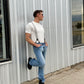 Handsome groom wearing light gray linen button-on suspenders with a rugged vintage menswear style. Handmade suspenders for weddings, groomsmen, and heritage fashion. Ethically crafted for classic sophistication and all-day comfort.