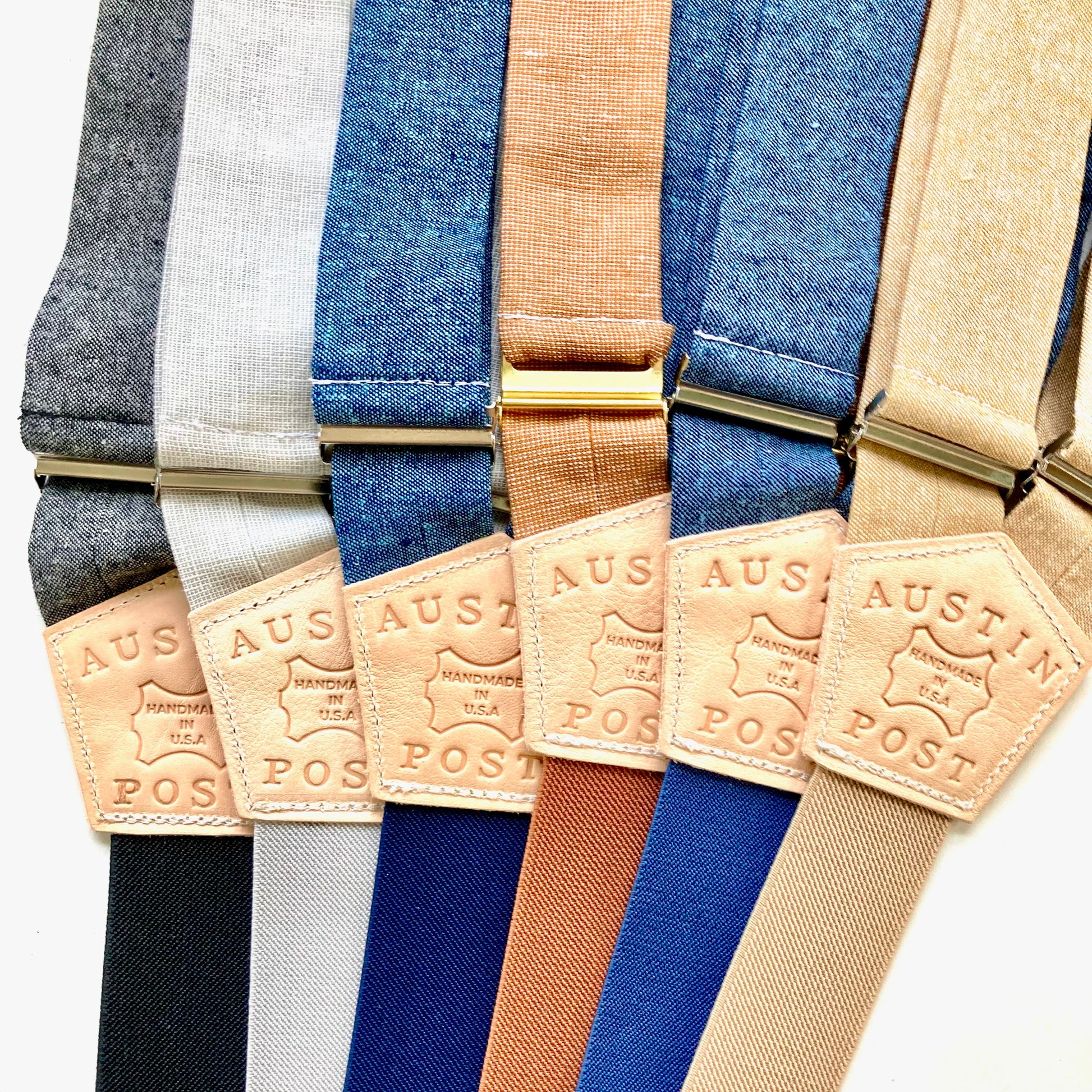 A collection of custom-order suspenders in monochrome shades of black, gray, navy, burnt orange, French blue, and tan. Featuring personalized vegetable-tanned leather back patches and premium metal hardware. Ideal for weddings, groomsmen, and timeless menswear. Handmade by Stratton Suspender Co.