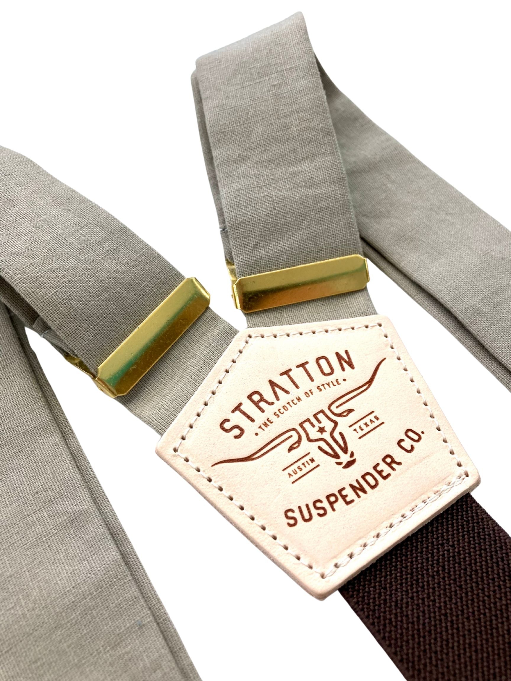 Close-up of Stratton’s Mushroom linen wedding suspenders featuring soft beige-taupe straps, golden brass adjusters, and the brand’s signature leather patch over a dark brown elastic back strap.