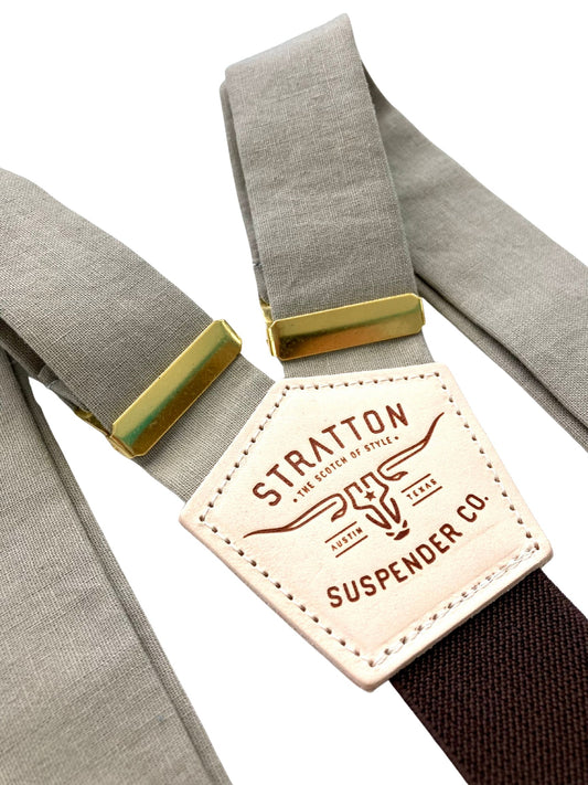 Close-up of Stratton’s Mushroom linen wedding suspenders featuring soft beige-taupe straps, golden brass adjusters, and the brand’s signature leather patch over a dark brown elastic back strap.