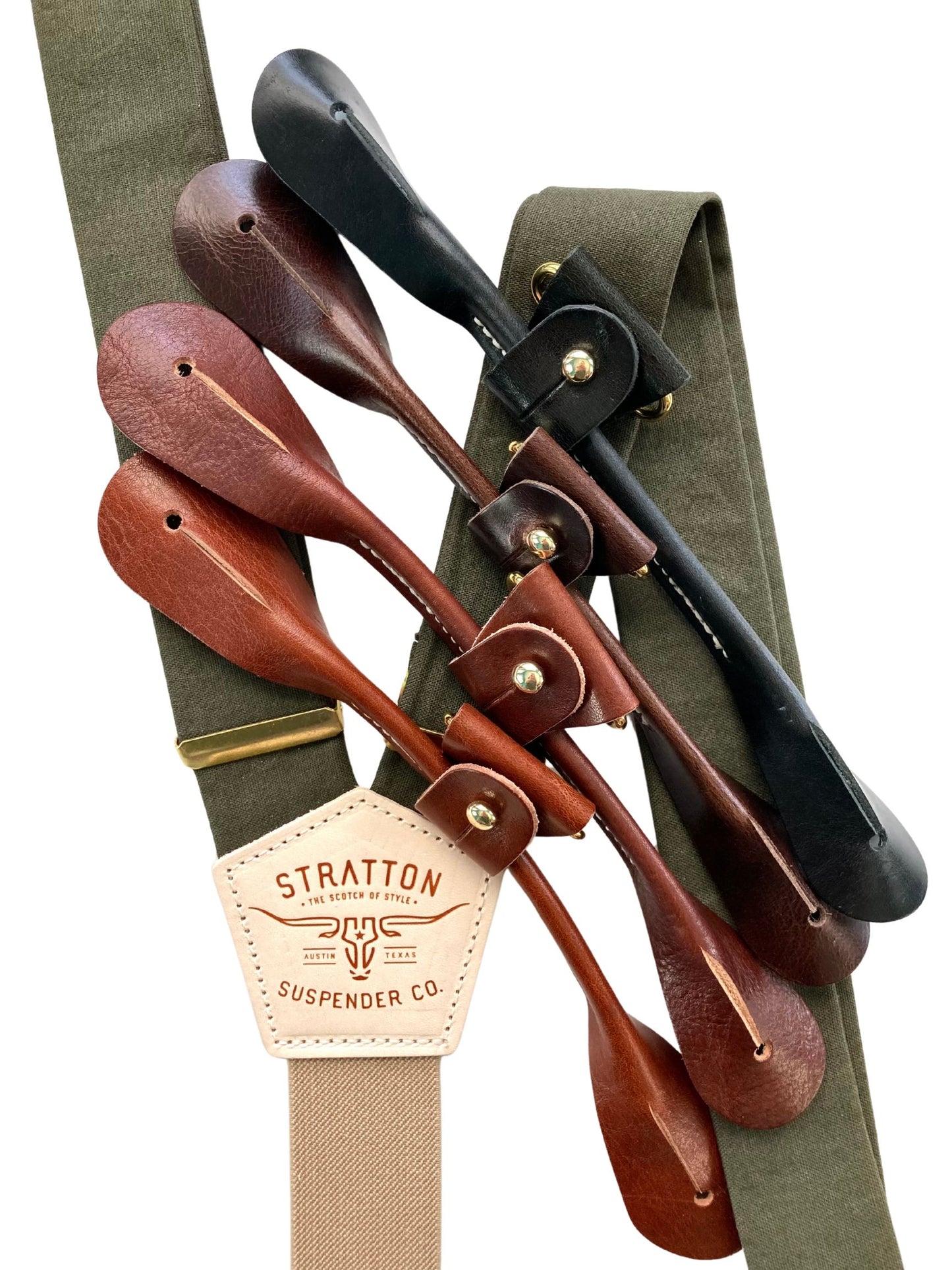 Close-up of olive green linen suspenders with a taupe back strap, brass hardware, and interchangeable full-grain leather button attachments in black, chocolate, cognac, and tan. A premium accessory for weddings, groomsmen, and heirloom menswear.