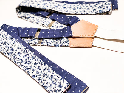 Handmade wedding suspenders in sapphire blue floral and vintage blue polka dot patterns, crafted with premium veg-tan leather back patch and white woven elastic straps. Designed for grooms, groomsmen, and vintage menswear enthusiasts, these button-on suspenders offer timeless style for formal events, rustic weddings, and classic gentleman's attire. Perfect for pairing with navy suits, linen wedding looks, or tailored menswear.