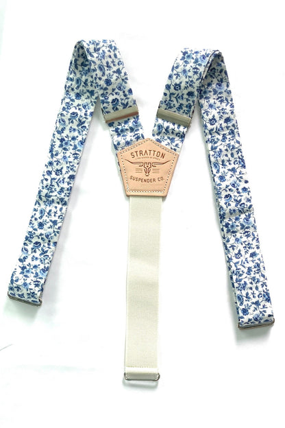 Flat-lay image of Sapphire Blue Floral wedding suspenders, featuring a delicate vintage-inspired blue floral pattern on premium linen straps. Designed with a full-grain vegetable-tanned leather back patch, polished silver-tone hardware, and a soft woven elastic back strap for comfort and flexibility. These button-on suspenders are perfect for grooms, groomsmen, and vintage wedding themes, offering a refined, tailored look superior to clip-ons. Handmade for formalwear, rustic weddings, and timeless menswear 
