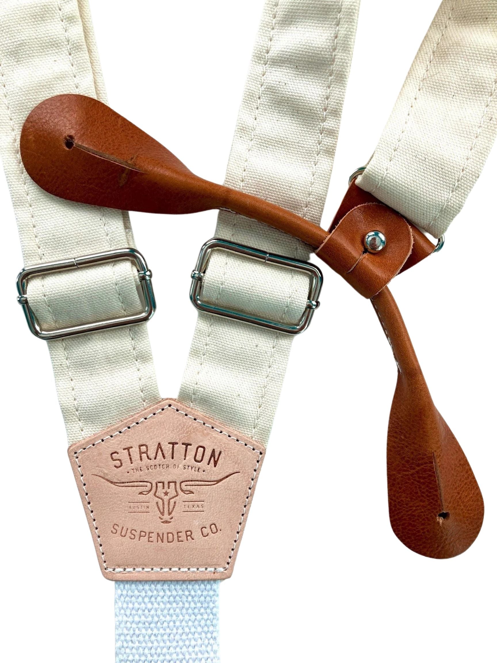 Rustic beige canvas button-on suspenders with tan full-grain leather attachment tabs, antique brass adjusters, and heavyweight cotton back strap; handcrafted braces for vintage-inspired menswear, rustic weddings, or rugged formalwear.
