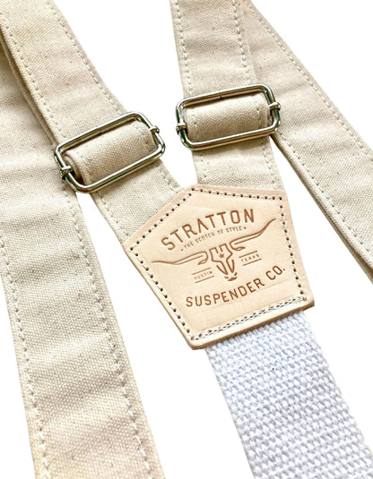 Close-up of beige rustic canvas wedding suspenders featuring antique brass adjusters, heavyweight cotton webbing back strap, and full-grain leather patch; handcrafted in the USA for groomsmen and western wedding attire.