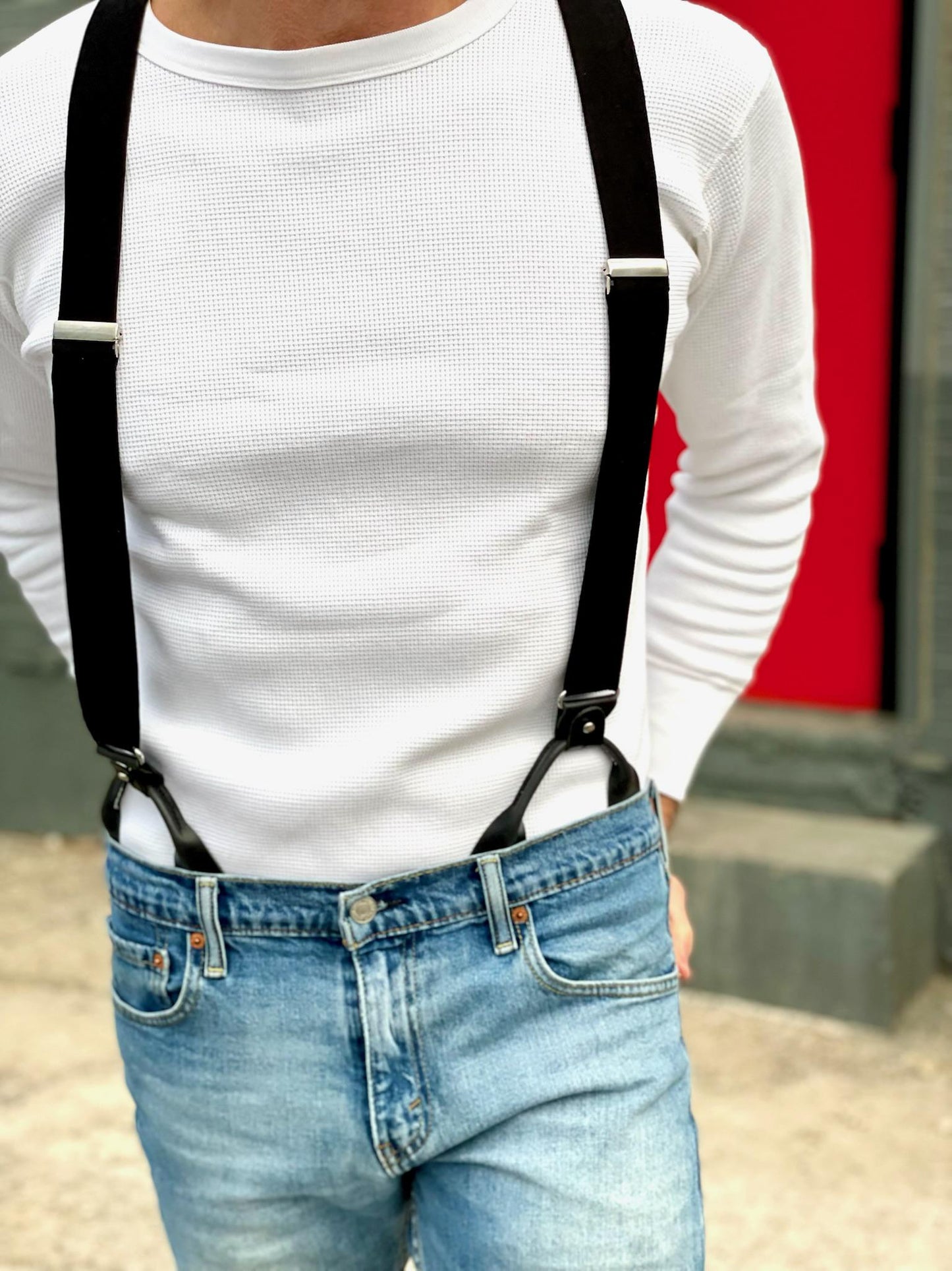 Close-up of a model wearing black linen button-on suspenders with silver hardware, paired with a white thermal shirt and classic Levi’s jeans—handmade leather braces for groomsmen, weddings, or everyday vintage menswear style.
