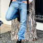 Man wearing black button-on suspenders with light-wash denim jeans and black boots, leaning casually against a tree. Classic vintage-style suspenders, handmade in the USA for groomsmen, weddings, and everyday wear.