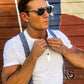 Denim blue linen suspenders with chestnut leather button-on ends, styled with a cream henley in front of the iconic Broken Spoke in Austin, Texas. Handmade by Stratton Suspender Co. for modern heritage menswear and wedding styling.