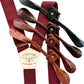 Bordeaux linen wedding suspenders with premium leather button-on tabs shown in black, chocolate, cognac, and tan with gold hardware.