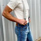 Charcoal linen button-on suspenders with black leather attachments, paired with a fitted white t-shirt and vintage Levi’s denim. A handcrafted wedding and groomsmen accessory, designed for rustic weddings, heritage menswear, and timeless American style. Ethically made in the USA.