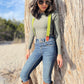 Women's Chartreuse Green Magnetic Suspenders with Cognac Leather Attachments by Stratton Suspender Co. – Styled with vintage denim, aviator sunglasses, and brown boots against a rustic tree backdrop. Handmade in Texas with premium linen straps and vintage-inspired magnetic clasps. Perfect for Western Chic and boho fashion.
