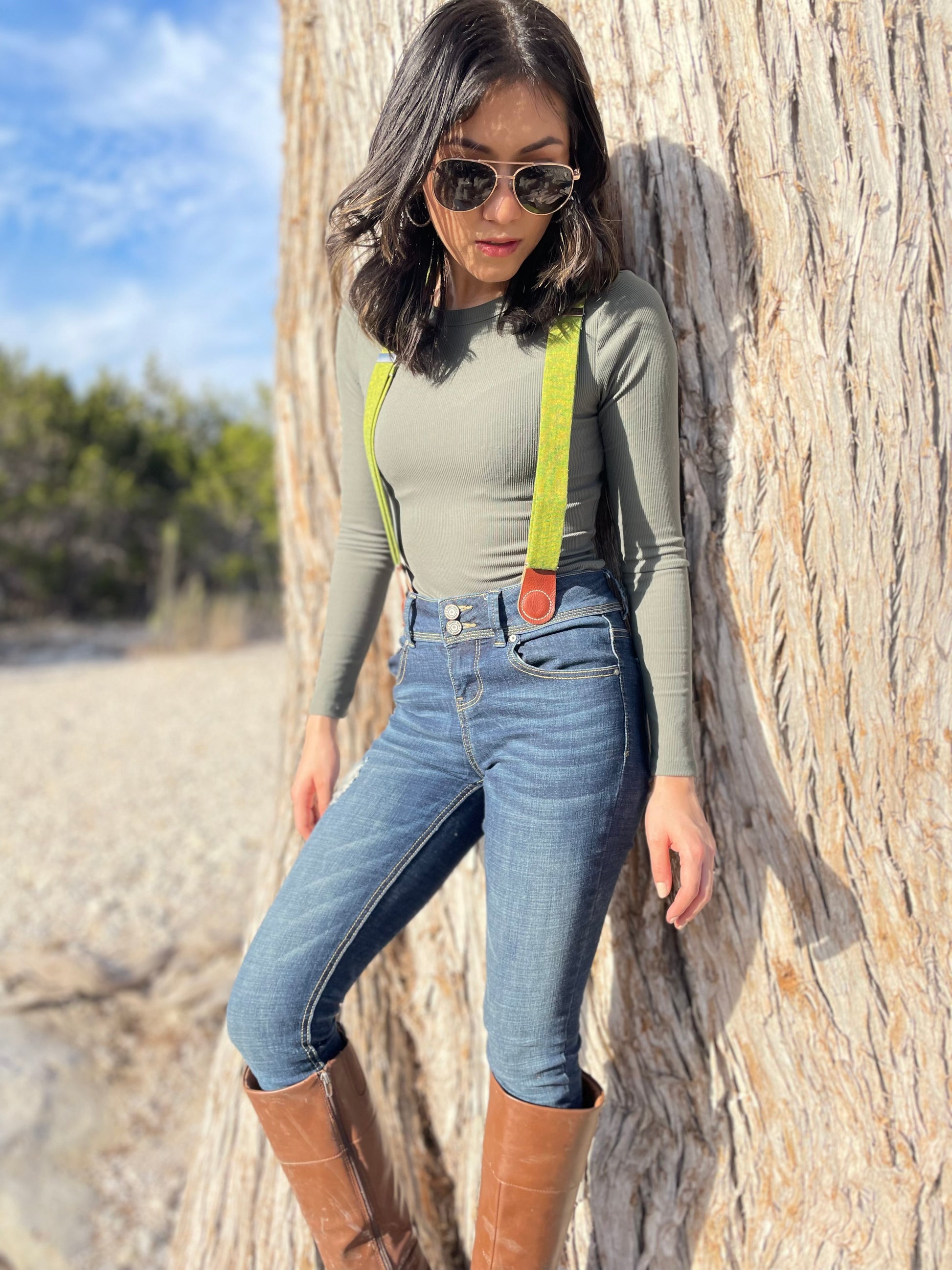 Women's Chartreuse Green Magnetic Suspenders with Cognac Leather Attachments by Stratton Suspender Co. – Styled with vintage denim, aviator sunglasses, and brown boots against a rustic tree backdrop. Handmade in Texas with premium linen straps and vintage-inspired magnetic clasps. Perfect for Western Chic and boho fashion.