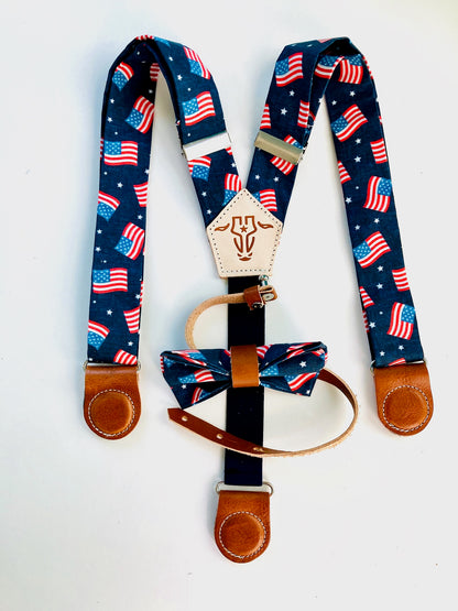 Kids’ patriotic suspenders featuring a USA flag print, tan leather magnetic clasps, and a coordinating bow tie for Independence Day events.