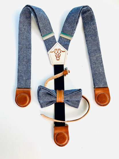 Kids' magnetic clasp suspenders in chambray-style blue linen with tan leather details and a coordinating bow tie for formal occasions.