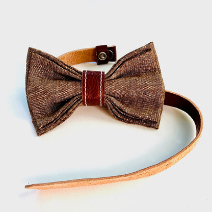 Children’s brown linen pre-tied bow tie with a cognac leather center wrap and adjustable leather neck strap.