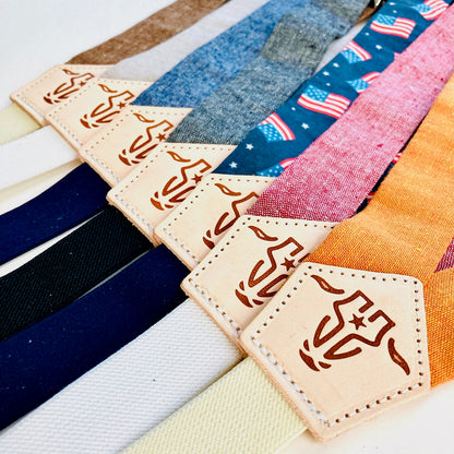 Close-up of children’s magnetic clasp suspenders in assorted colors, featuring linen straps and leather back patches with embossed logo.